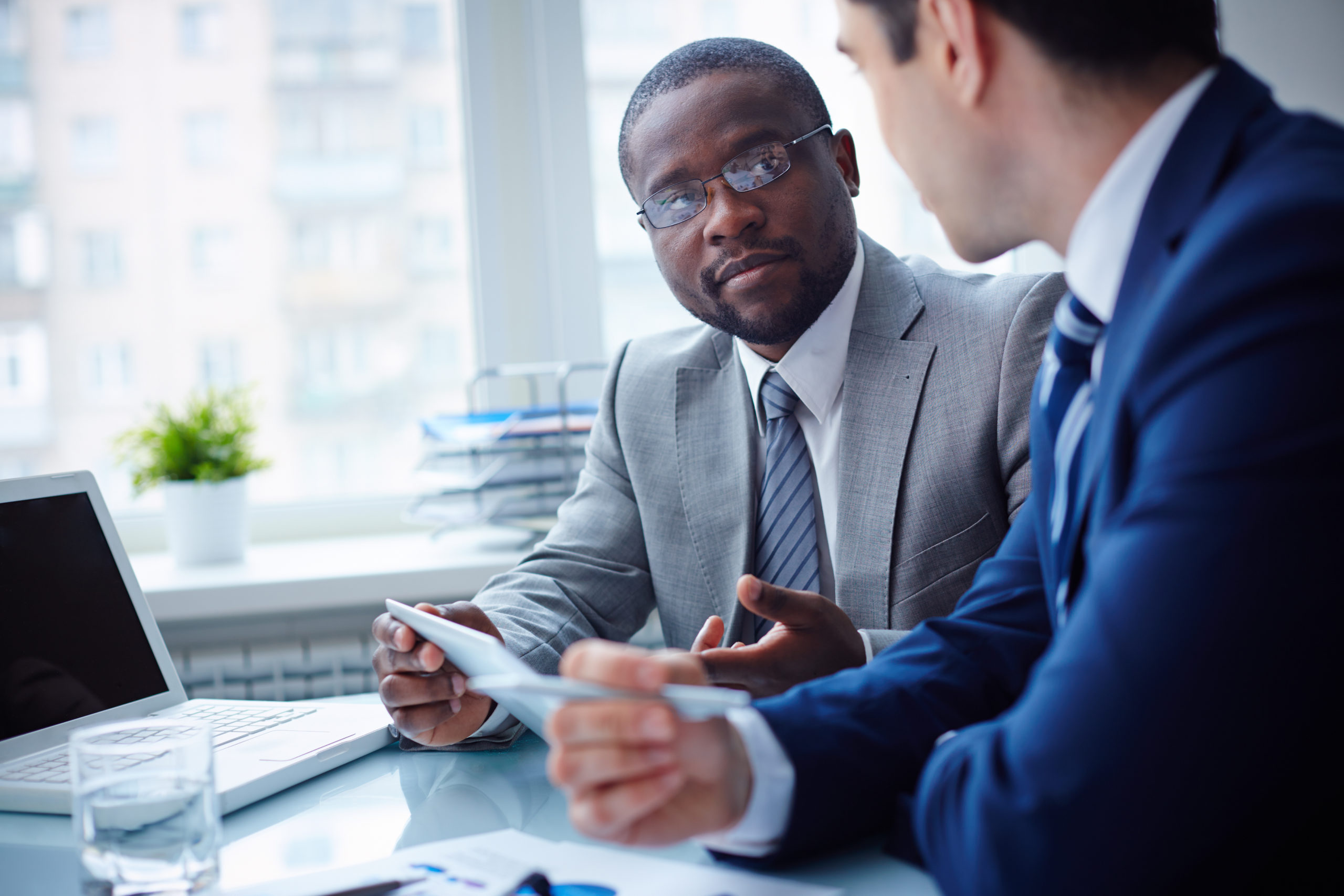 Image of two young businessmen interacting at meeting in office